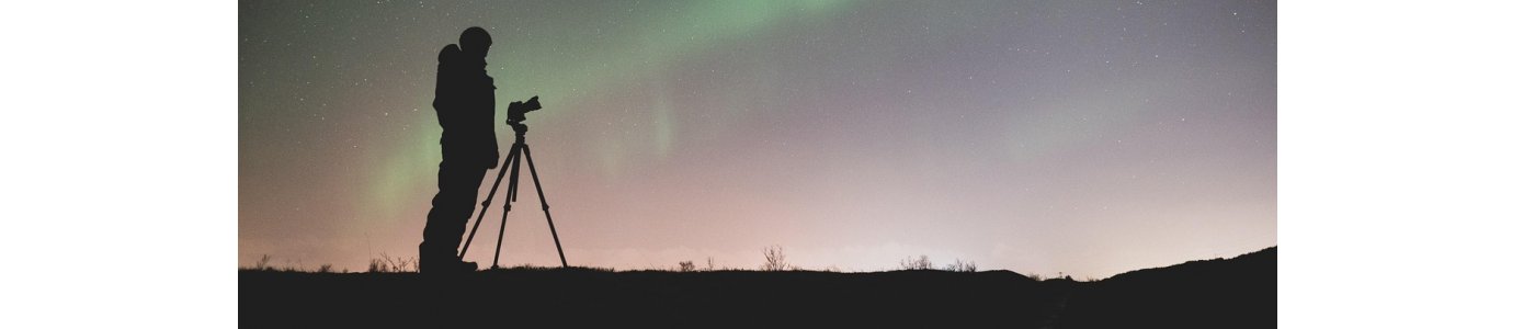 A person with a tripod and camera standing there taking pictures of the Aurora