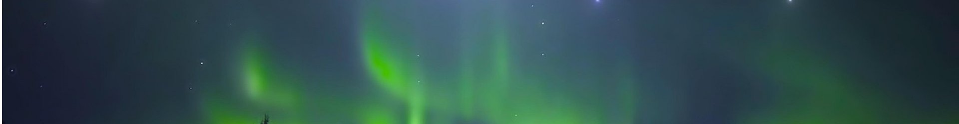 Bright green auroras glowing across a dark Alaska night sky during a Northern Lights display.